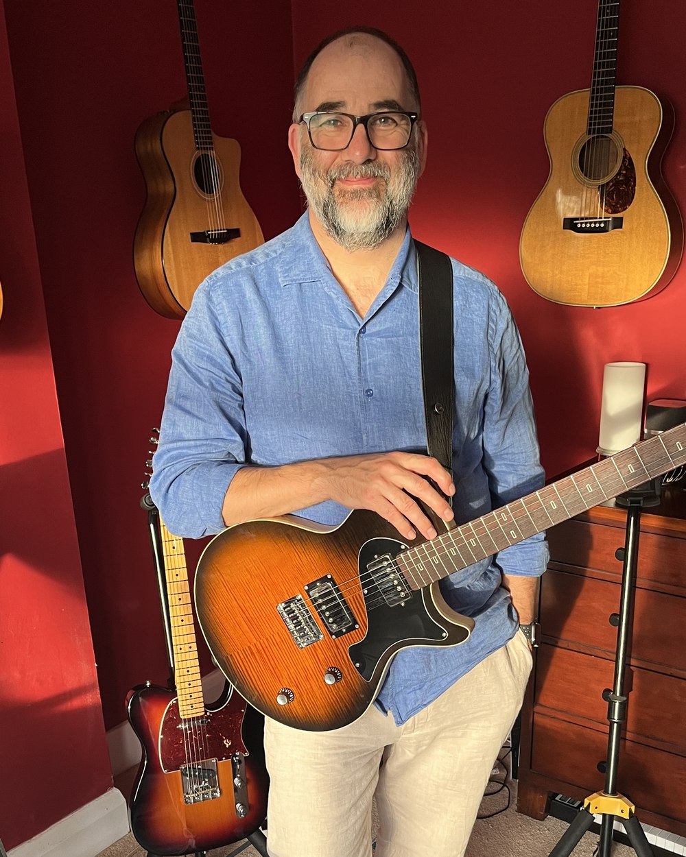 Steven Randell holding an electric guitar in his Bromley home studio